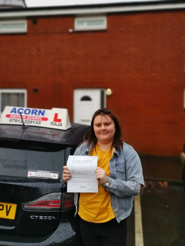 Student holding driving test certificate after passing in Blackburn
